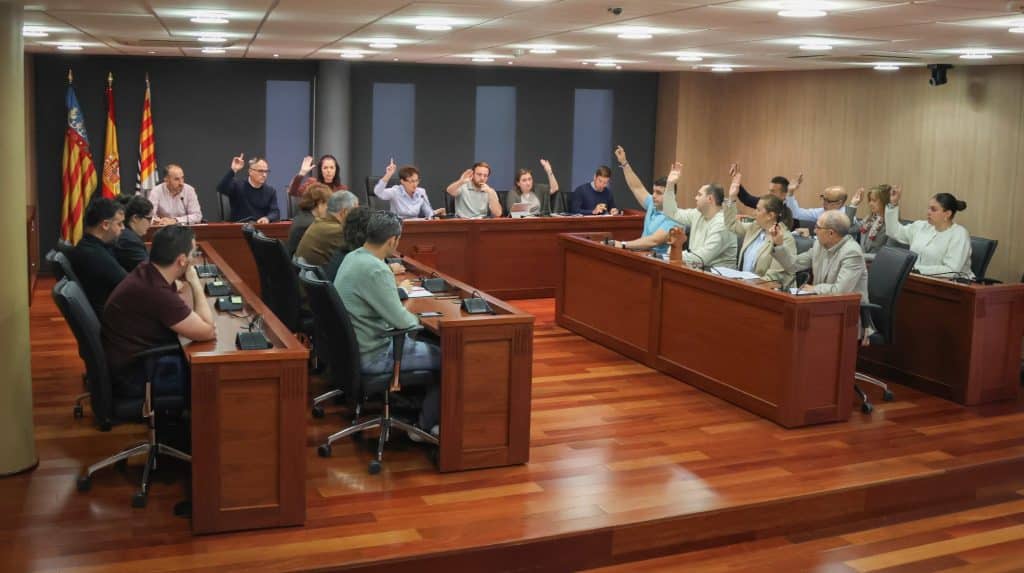 Representantes políticos del Ayuntamiento de Onda levantando la mano durante una votación en el pleno municipal de mayo sobre políticas de bienestar social y vivienda.